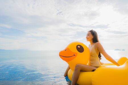 Portrait young asian woman on inflatable float yellow duck around outdoor swimming pool in hotel and resort for holiday vacation conceptの写真素材