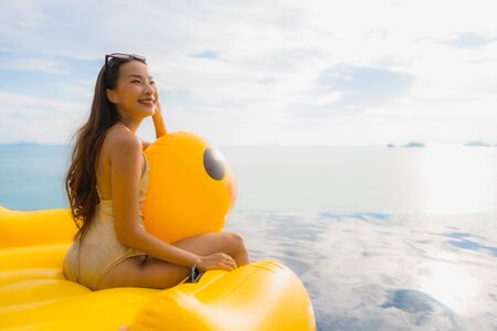 Portrait young asian woman on inflatable float yellow duck around outdoor swimming pool in hotel and resort for holiday vacation conceptの写真素材