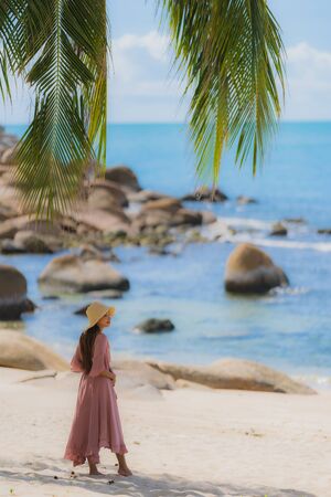 Portrait young asian woman smile happy around beach sea ocean with coconut palm tree for travel in holiday vacationの写真素材