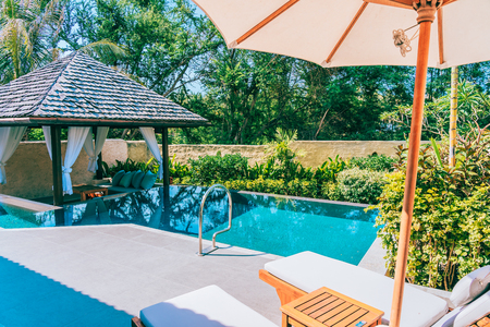 Umbrella and chair around swimming pool neary beautiful landscape of sea ocean beach with blue sky and white cloud for leisure travel and vacationのeditorial素材