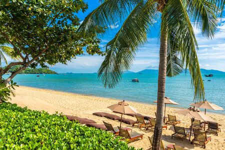 Beautiful tropical beach sea and ocean with coconut palm tree  and umbrella and chair on blue sky...