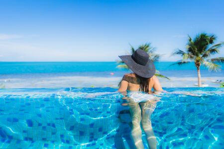 Portrait beautiful young asian woman relax in luxury outdoor swimming pool in hotel resort nearly beach sea ocean for holiday vacation conceptの写真素材