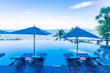 Umbrella and chair around beautiful luxury outdoor swimming pool with sea ocean view in hotel resort for holiday vacation travel conceptの写真素材