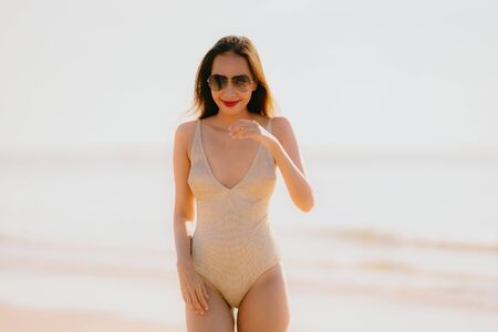 Portrait young beautiful asian woman walk smile happy on the beach sea ocean with sunglasses for leisure travel in holiday vacationの写真素材