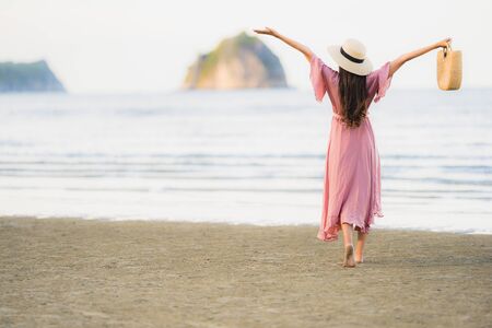 Portrait young beautiful asian woman walk smile and happy on the beach sea and ocean for leisure travel in holiday vacationの写真素材