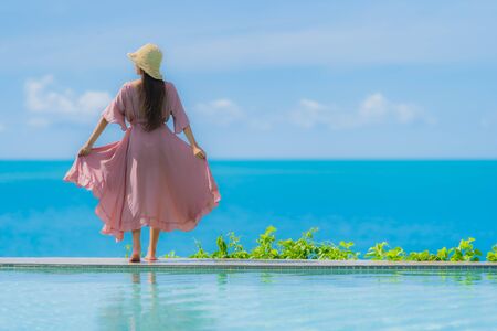 Portrait young asian woman relax smile happy around outdoor swimming pool with sea ocean view in holiday vacation conceptの写真素材