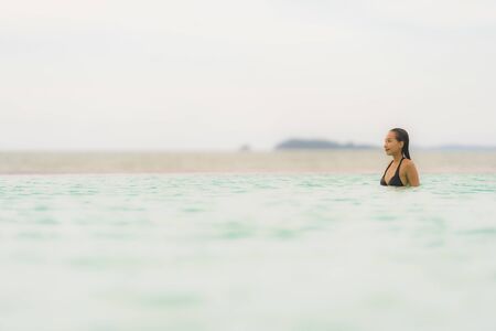 Portrait beautiful young asian woman wear bikini around swimming pool in hotel resort nearly sea ocean beach for leisure relax in holiday vacation timeの写真素材