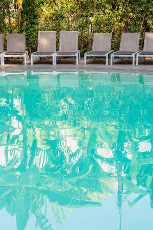 Empty chair around swimming pool in hotel resort for travel leisure and vacation conceptの写真素材