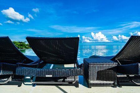 Umbrella and chair around swimming pool in hotel resort neary sea ocean beach for leisure relax in...