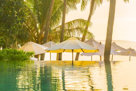 Beautiful outdoor tropical nature landscape of swimming pool with coconut palm tree umbrella and...