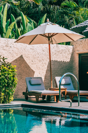 Umbrella and chair around swimming pool neary beautiful landscape of sea ocean beach with blue sky and white cloud for leisure travel and vacationのeditorial素材