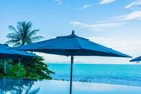 Umbrella and chair around beautiful luxury outdoor swimming pool with sea ocean view in hotel resort for holiday vacation travel conceptの写真素材