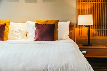Comfortable pillow on bed with light lamp furniture decoration interior of hotel bedroomの写真素材
