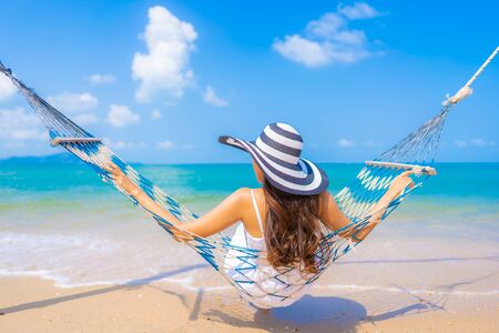 Portrait beautiful young asian woman happy smile leisure on hammock swing around the beach sea and ocean with blue sky white cloud for vacation travelの写真素材