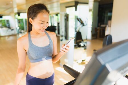 Portrait beautiful asian young woman using mobile phone in gym room