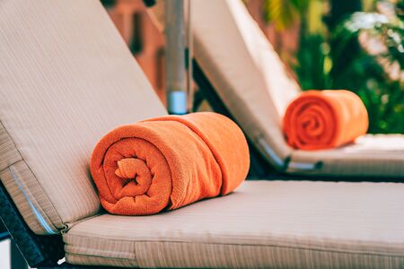Orange pool towel on deck chair around swimming pool in hotel resort for vacation travel and leisureの写真素材