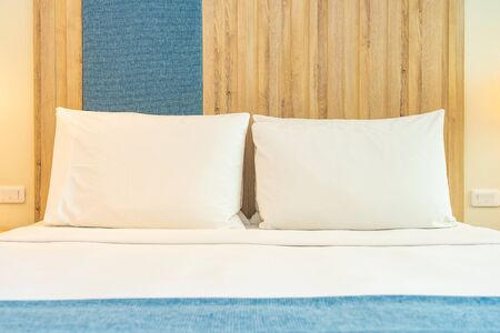 White comfortable pillow on bed decoration with light lamp interior of room