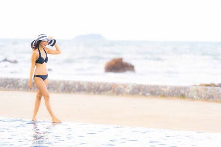 Portrait beautiful young asian woman wear bikini around swimming pool in hotel resort nearly sea ocean beach for leisure relax in holiday vacation timeの写真素材