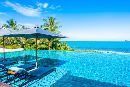 Beautiful luxury outdoor swimming pool in hotel resort with sea ocean around coconut palm tree and white cloud on blue sky for holiday vacation travelの写真素材