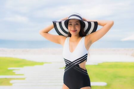 Portrait beautiful young asian women happy smile relax around swimming pool near sea beach ocean in hotel resortの写真素材