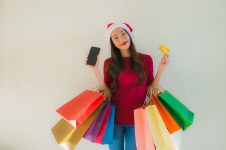 Portrait beautiful young asian women wear christmas santa hat with shopping bag smart mobile phone and credit cardの写真素材