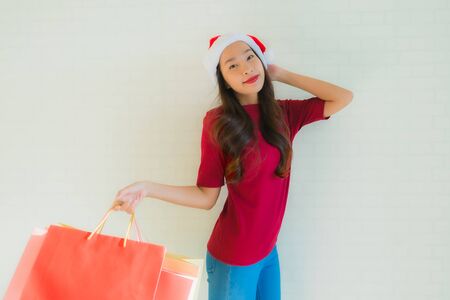 Portrait beautiful young asian women wear christmas santa hat with shopping bag from department storeの写真素材