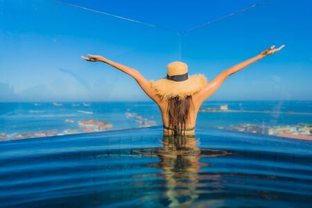 Beautiful young asian women happy smile relax around outdoor swimming pool in hotel resort near sea beach for travel in holiday vacationの写真素材
