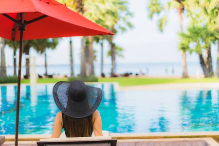 Portrait beautiful young asian women happy smile relax around swimming pool neary sea beach ocean in hotel resortの写真素材