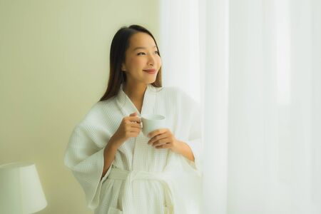Portrait beautiful young asian women with coffee cup in bedroom interiorの写真素材