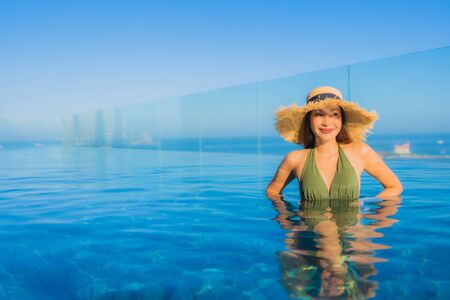 Beautiful young asian women happy smile relax around outdoor swimming pool in hotel resort neary sea...