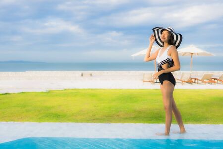 Portrait beautiful young asian women happy smile relax around swimming pool neary sea beach ocean in hotel resortの写真素材