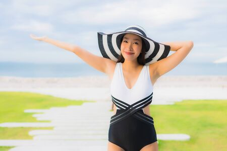 Portrait beautiful young asian women happy smile relax around swimming pool neary sea beach ocean in hotel resortの写真素材