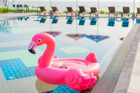 Flamingo float around swimming pool in hotel resort with umbrella and chair in hotel resort for...