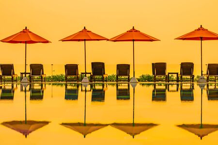 Beautiful sunrise around with umbrella and chair outdoor swimming pool for travel vacation
