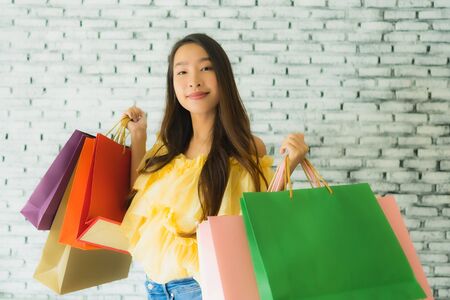 Portrait young asian woman holding colorful shopping bag with happy smileの写真素材