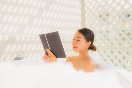 Portrait young asian woman read book in bathtub for spa conceptの写真素材