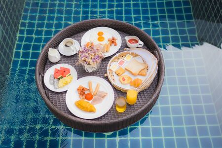 Breakfast set floating around swimming pool in hotel resortの写真素材