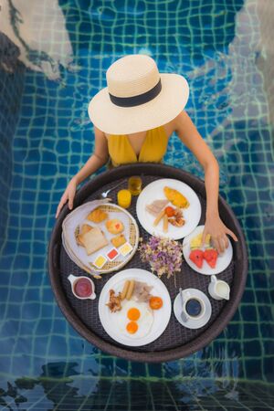 Portrait beautiful young asian woman happy smile relax with breakfast floating around swimming pool...