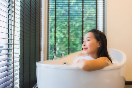 Portrait beautiful young asian woman happy smile relax take a bath in bathtub of bathroom interiorの写真素材