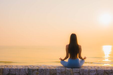 Portrait young asian woman do meditation around sea beach ocean at sunrise for healthの写真素材