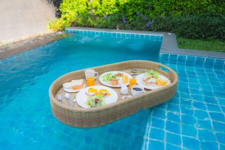 Floating breakfast around outdoor swimming pool in hotel resortの写真素材