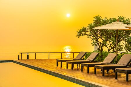 Beautiful sunrise around with umbrella and chair outdoor swimming pool for travel vacationの写真素材
