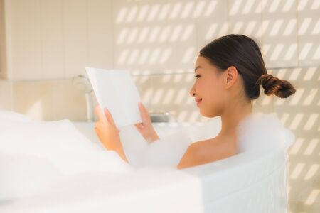 Portrait young asian woman read book in bathtub for spa conceptの写真素材
