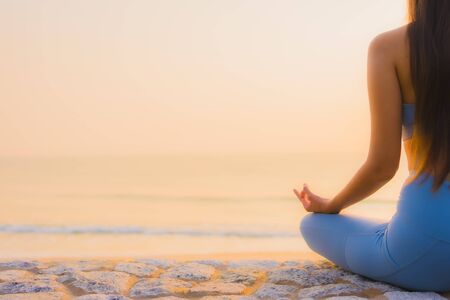 Portrait young asian woman do meditation around sea beach ocean at sunrise for healthの写真素材