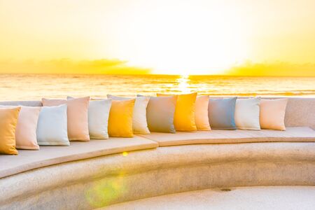 Comfortable pillow on sofa chair around outdoor patio with sea ocean beach view for travel vacation at sunriseの写真素材