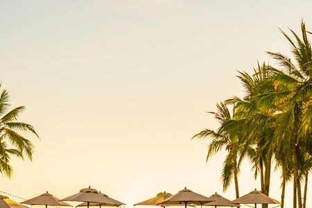 Beautiful tropical nature umbrella chair with palm tree around beach sea ocean at sunset or sunrise...