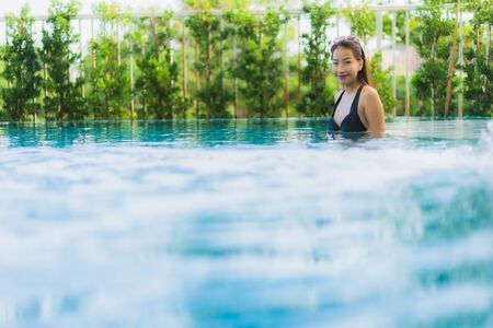 Portrait beautiful young asian women happy smile relax outdoor swimming pool in resort hotel for vacation travelの写真素材