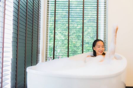 Portrait beautiful young asian woman happy smile relax take a bath in bathtub of bathroom interiorの写真素材