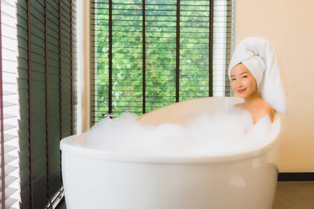 Portrait beautiful young asian woman happy smile relax take a bath in bathtub of bathroom interiorの写真素材