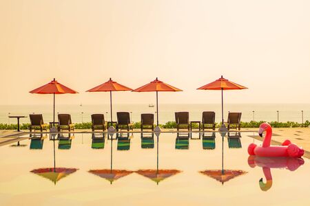 Beautiful sunrise around with umbrella and chair outdoor swimming pool for travel vacationの写真素材